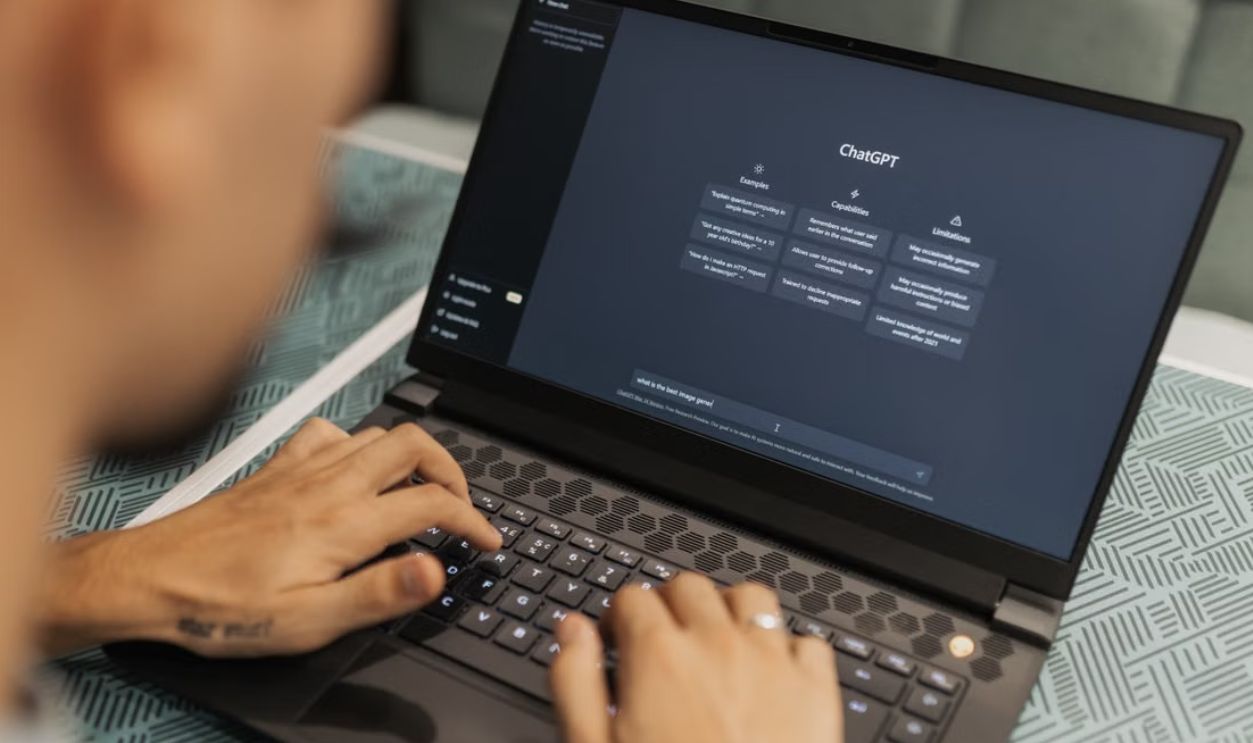 Close-up of a person typing on a laptop displaying the ChatGPT interface, emphasizing modern technology use
