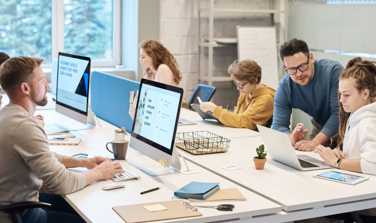 Team collaboration in a modern office setting with computers and diverse employees working together