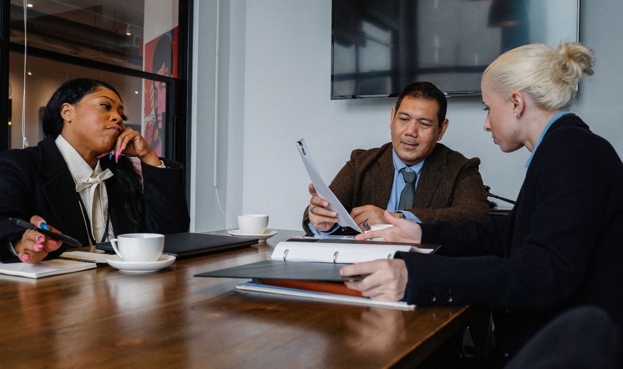 Business professionals collaborating in a diverse office setting, discussing a project around a table
