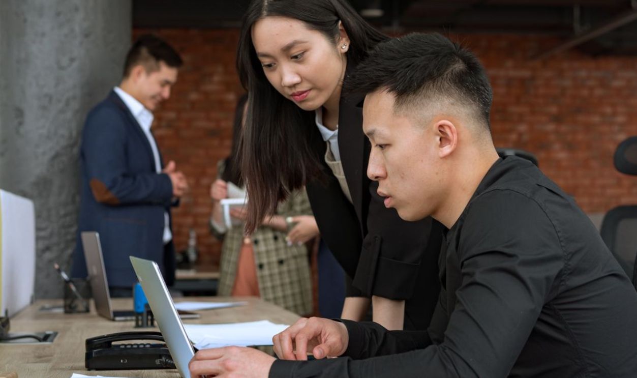 Professionals working together in a modern office setting around a laptop