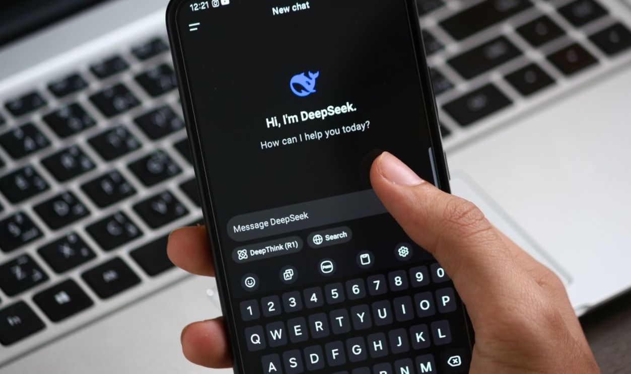 Person interacting with DeepSeek AI chat app on smartphone, focusing on digital innovation and communication.