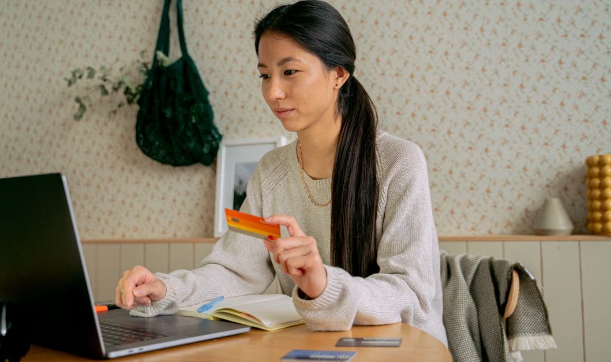 Young Asian woman using a laptop and credit card for online shopping at home