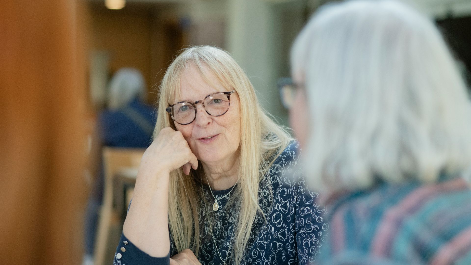 a woman sitting at a table with a cup of coffee