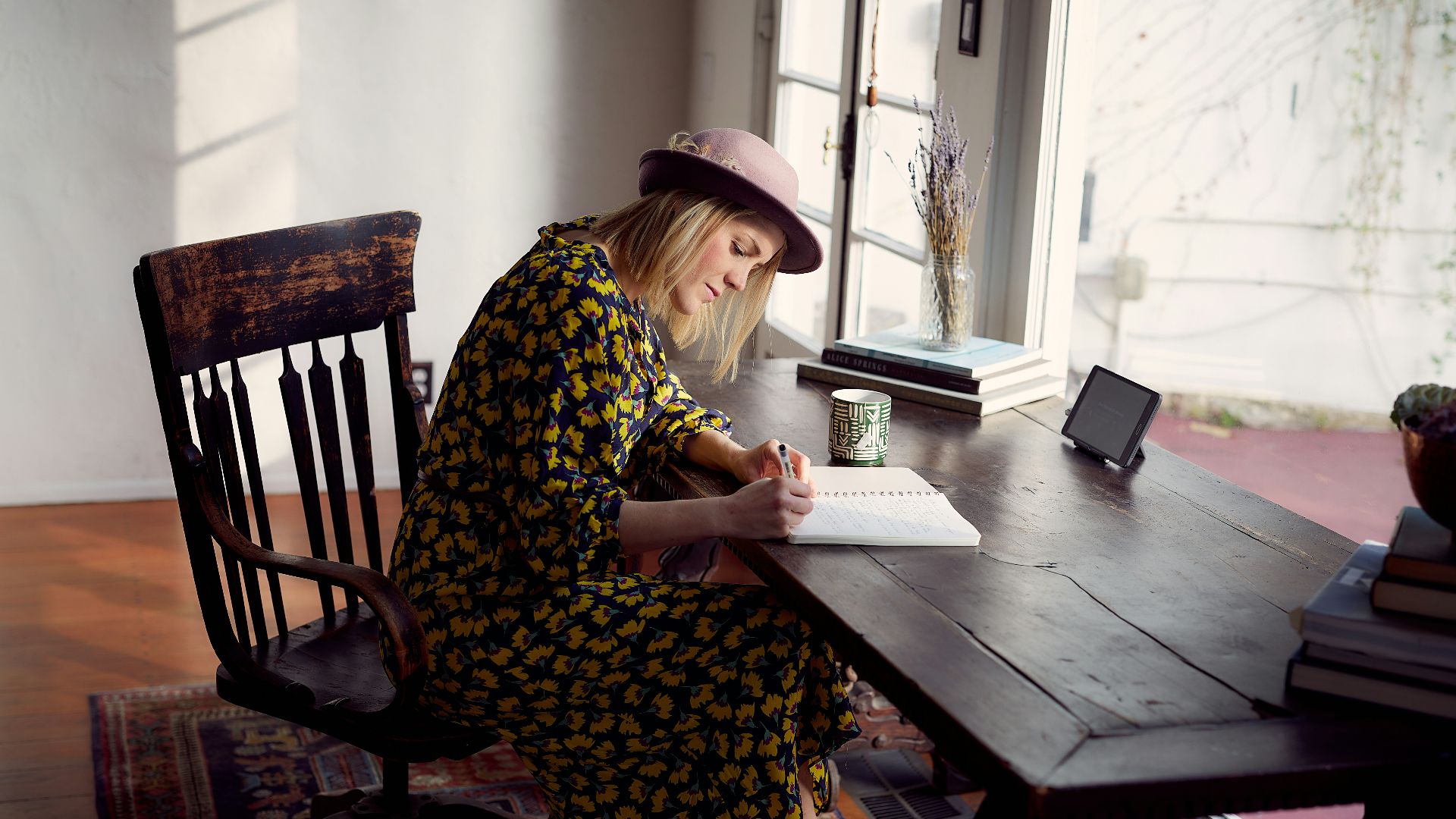 woman in yellow and black floral dress sitting on brown wooden chair