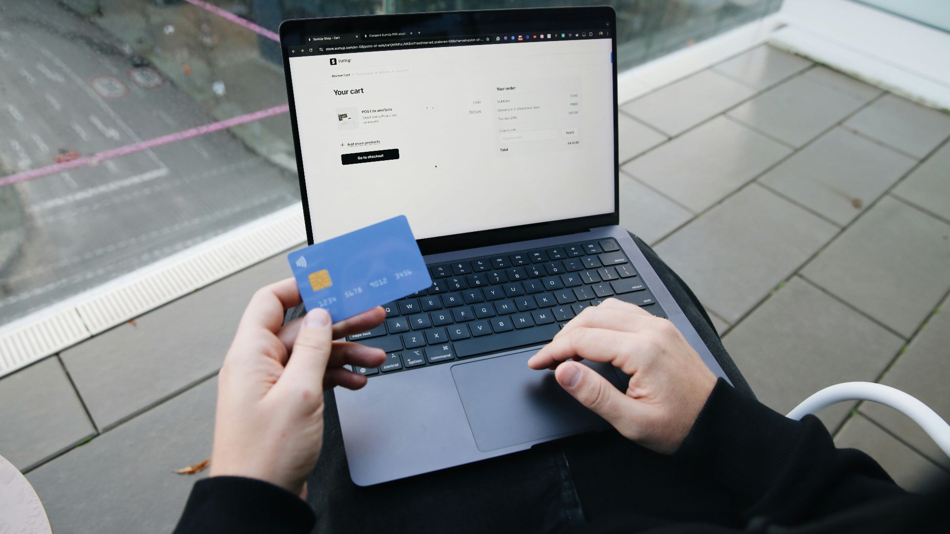 A person sitting in a chair with a laptop and a credit card