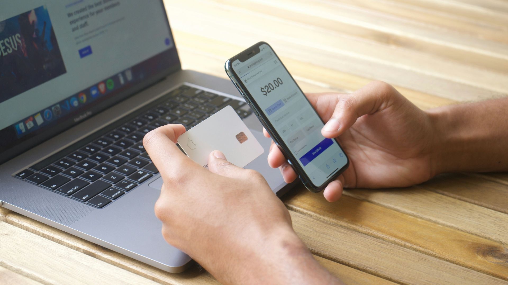 Person using smartphone and credit card with laptop