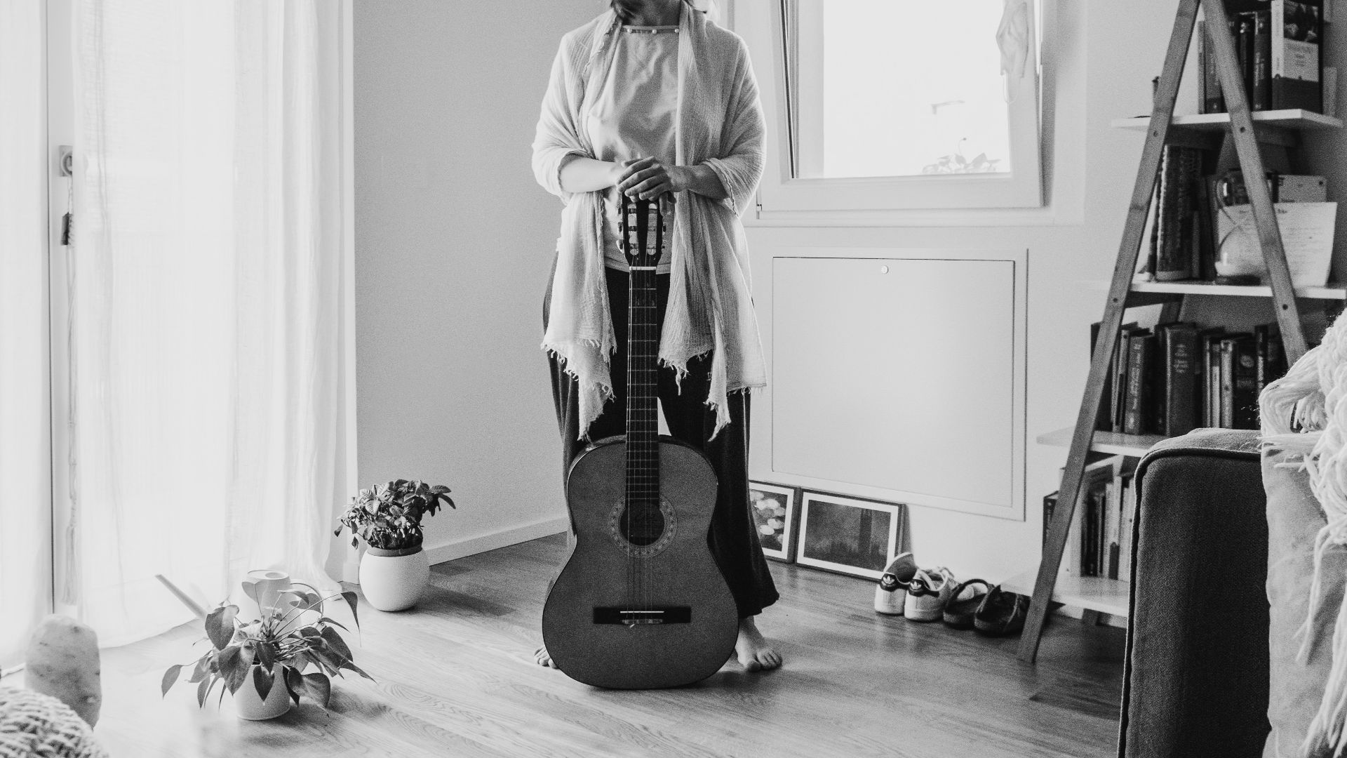 Woman with guitar standing indoors near window