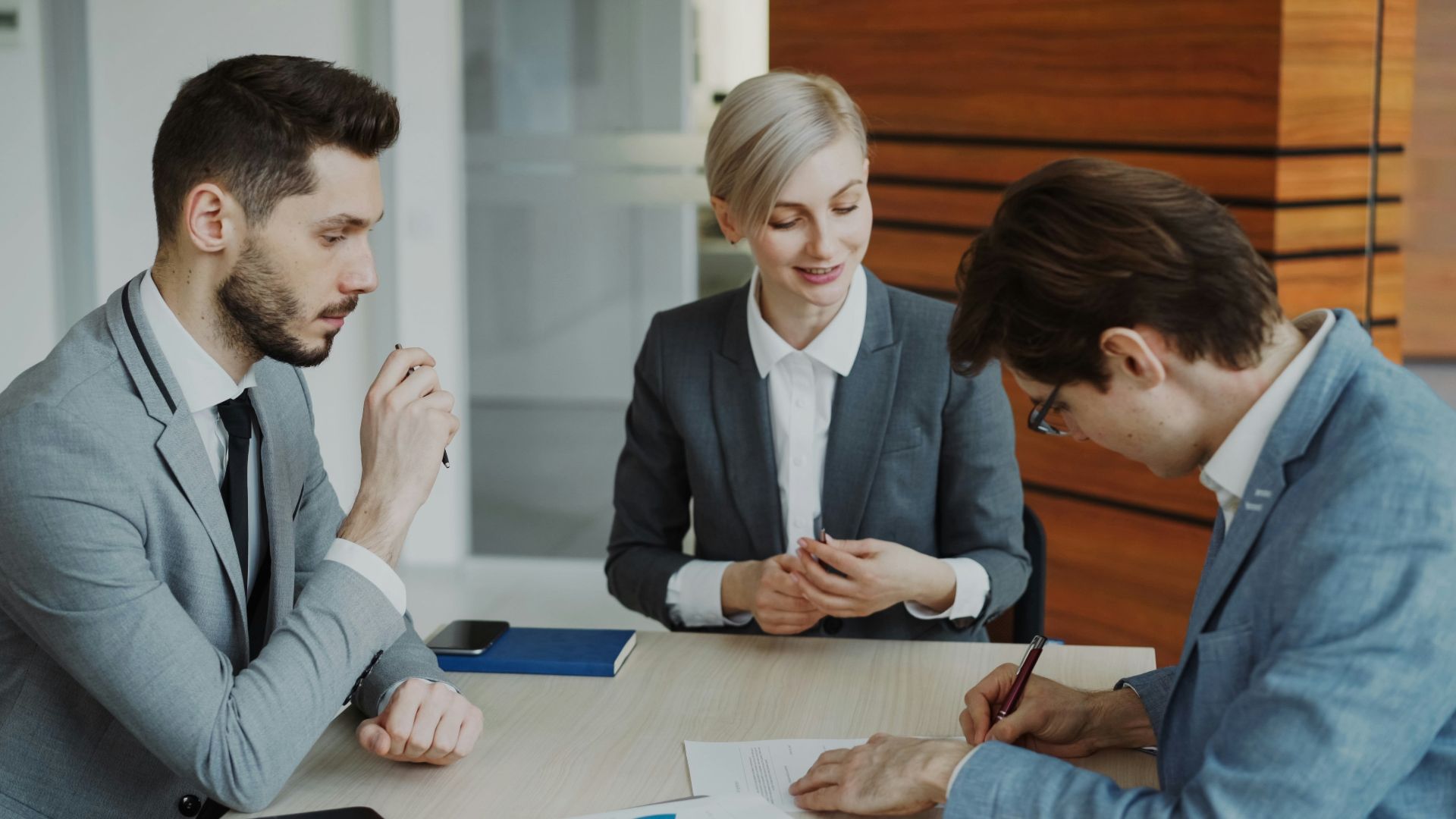 Business people signing a contract at a table.