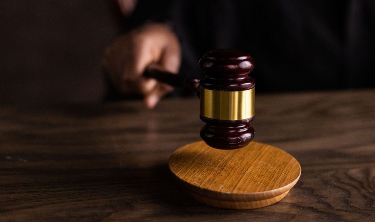 A gavel striking a sound block, symbolizing justice and legal authority in a courtroom setting.