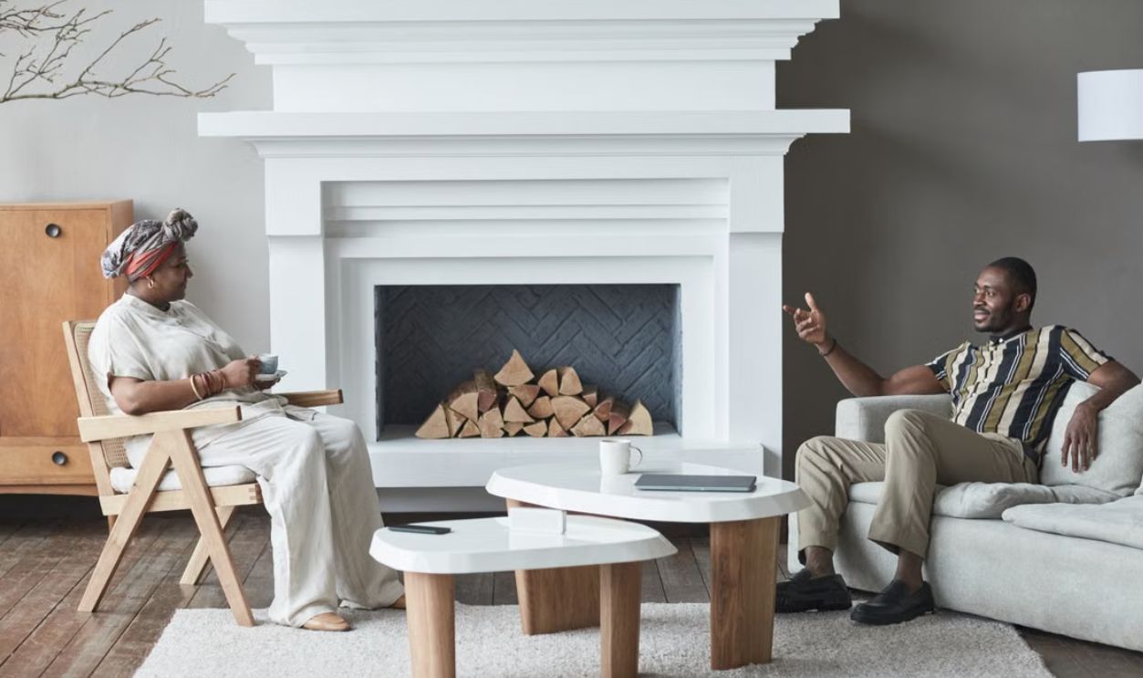 Two adults having a relaxed conversation in a stylish living room with a modern fireplace