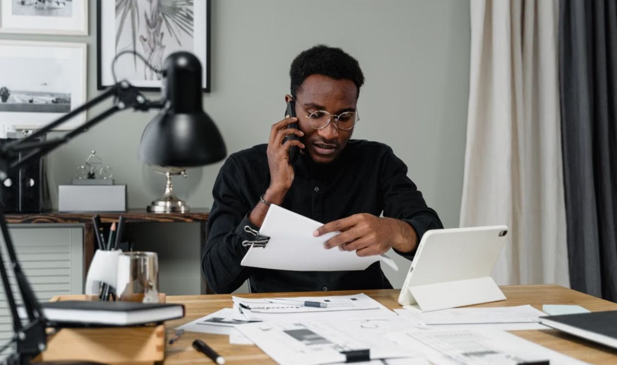 Focused businessman reviewing documents while speaking on phone in modern office