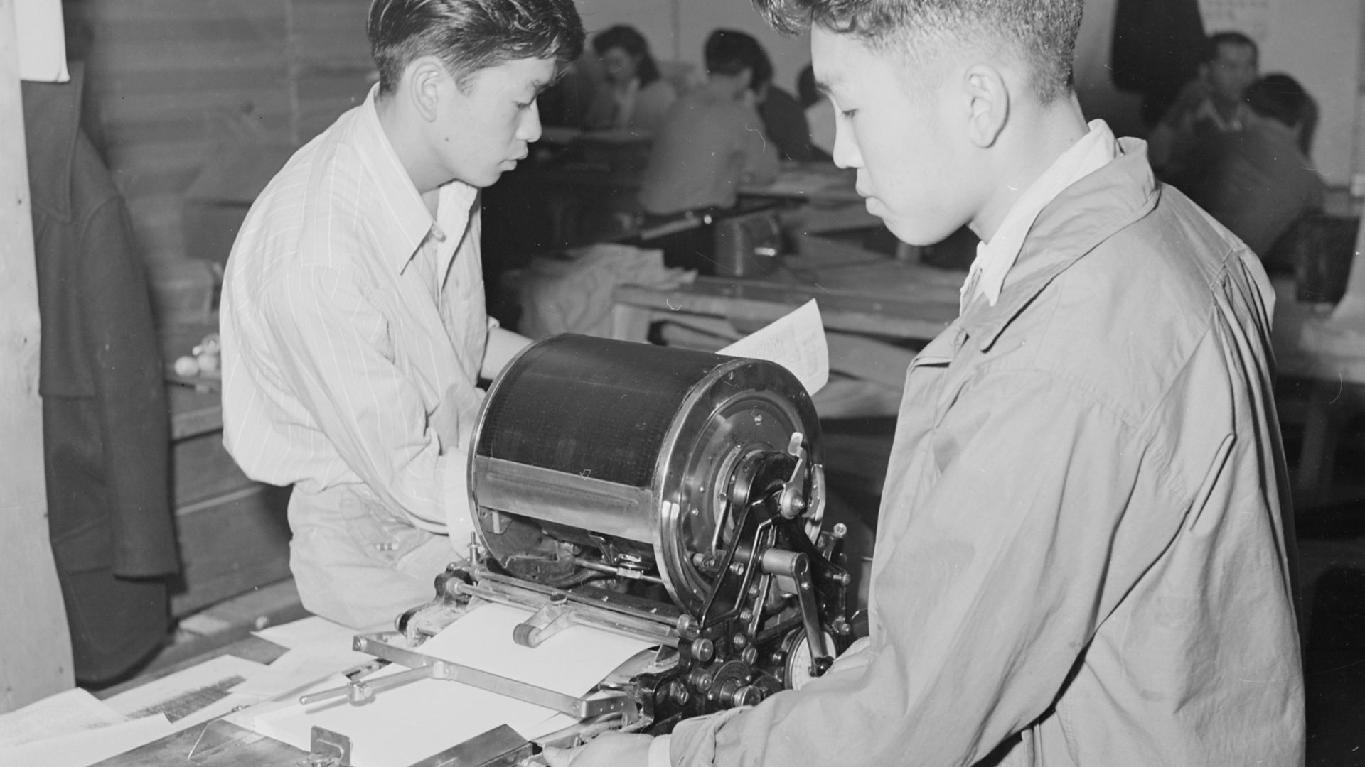 Scope and content:  The full caption for this photograph reads: Heart Mountain Relocation Center, Heart Mountain, Wyoming. Editor Albert Saijo inspects a copy of Echoes, high school paper, being run off on the mimeograph machine by Toyoji Sugita, staff ar