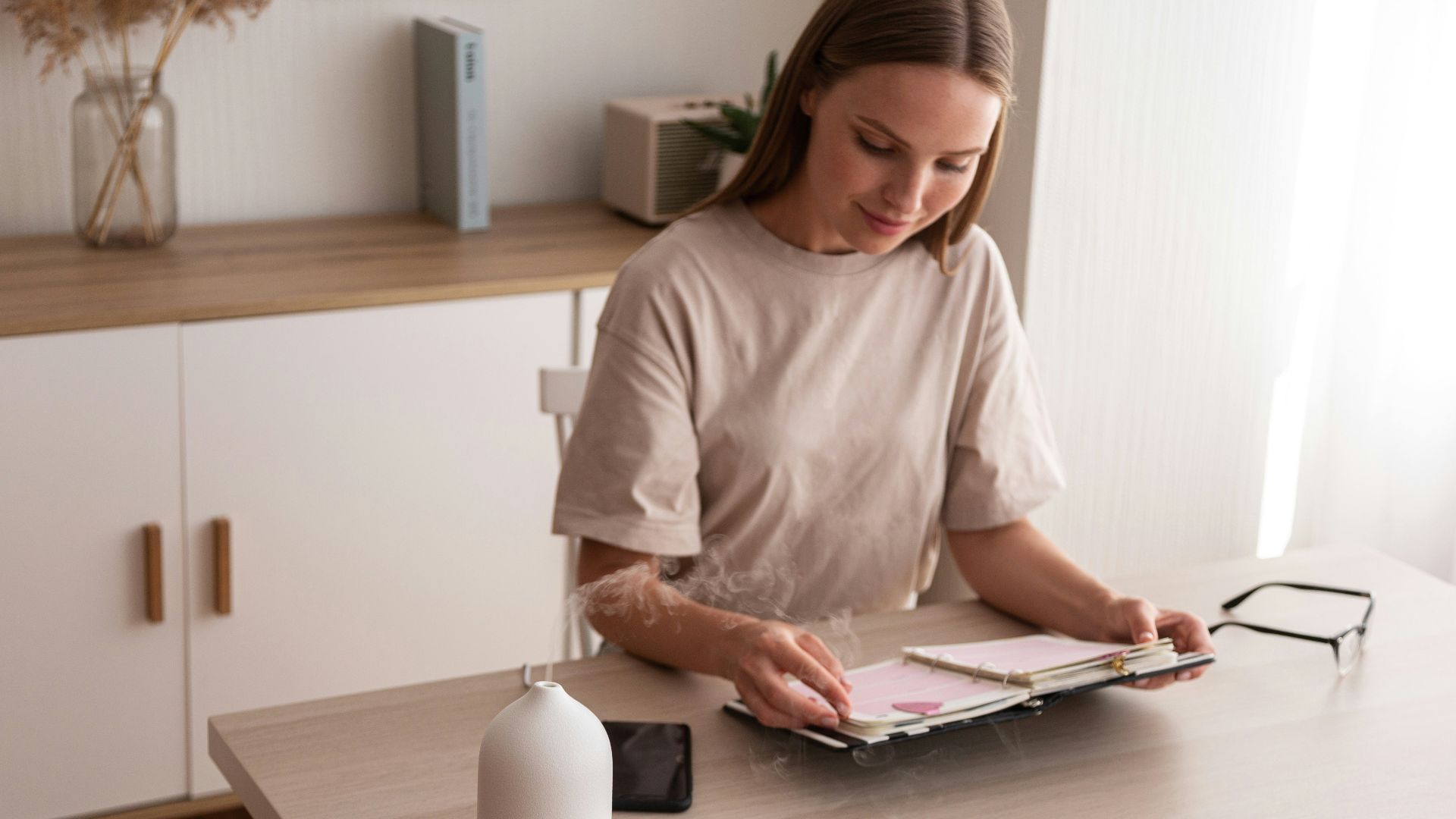 a woman sitting at a table looking at a book