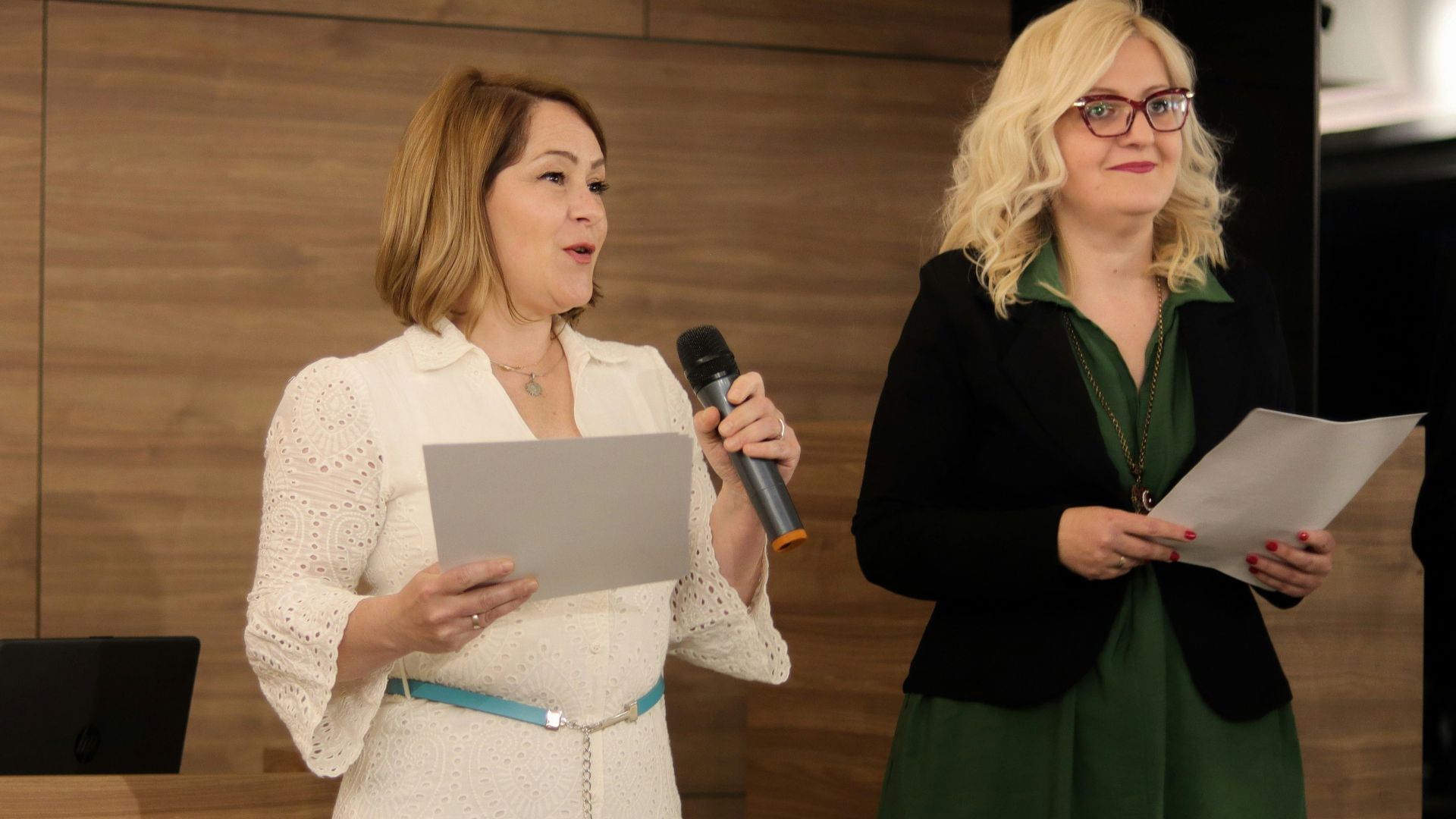 a woman standing next to a woman holding a microphone
