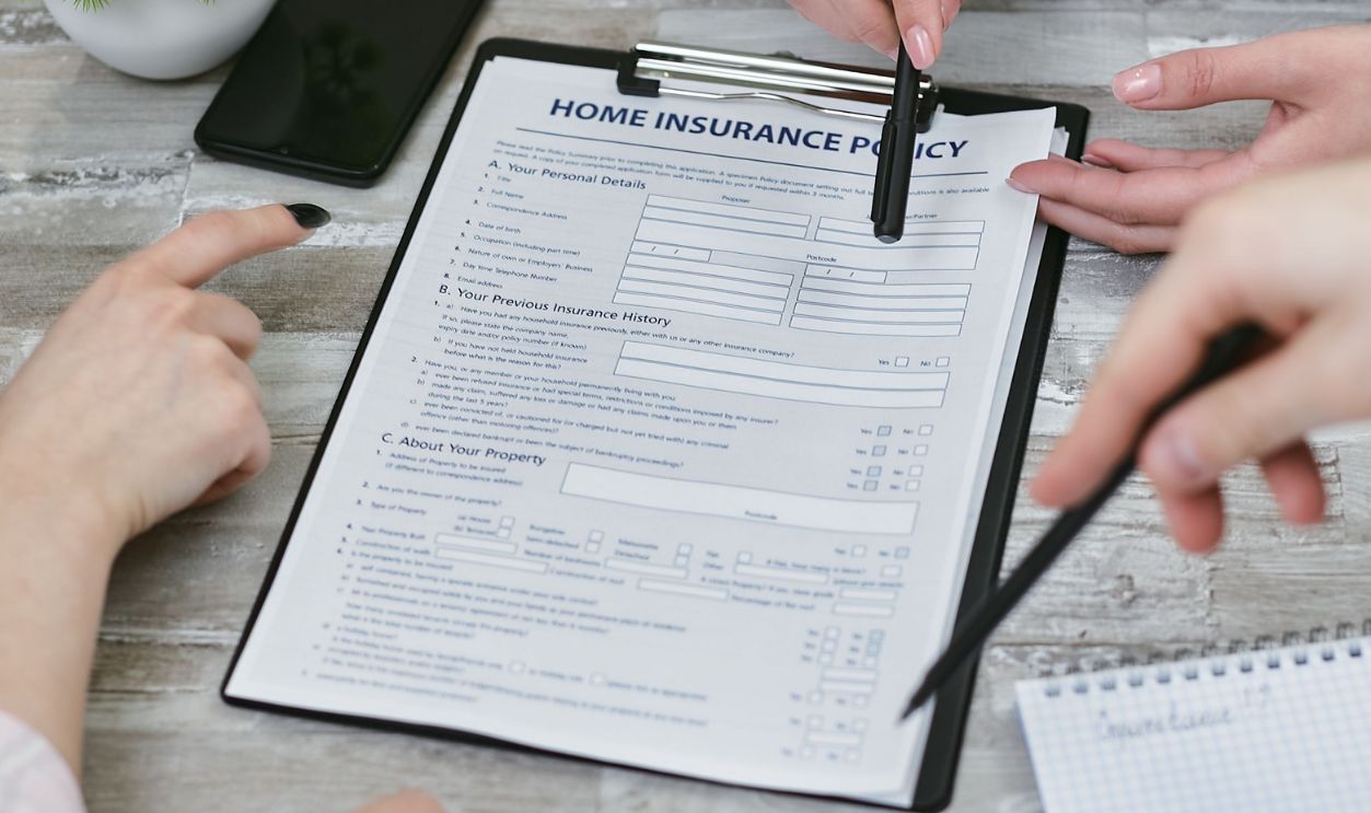 Three individuals collaborating on a home insurance policy document