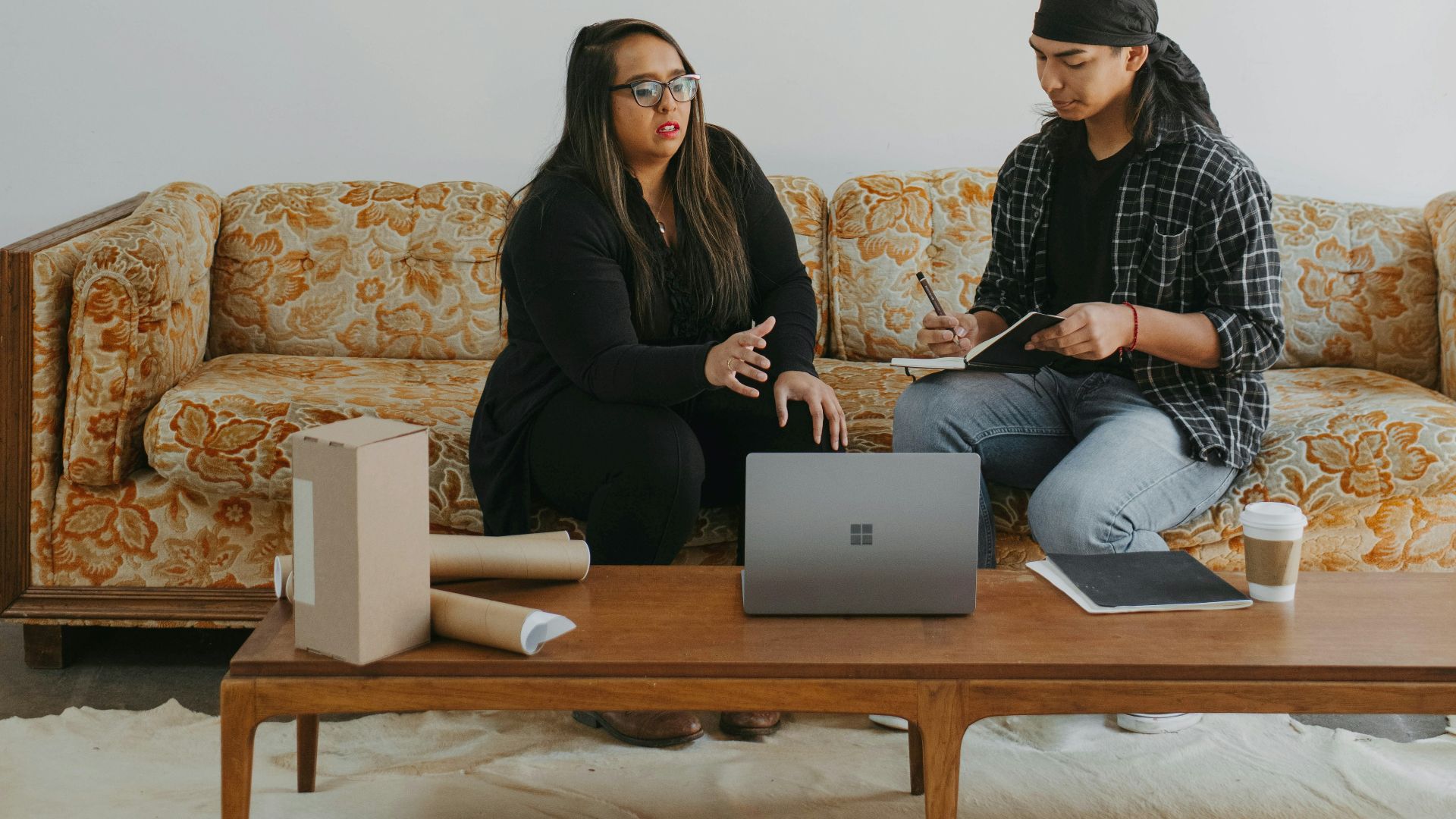 two people sitting on a couch looking at a laptop