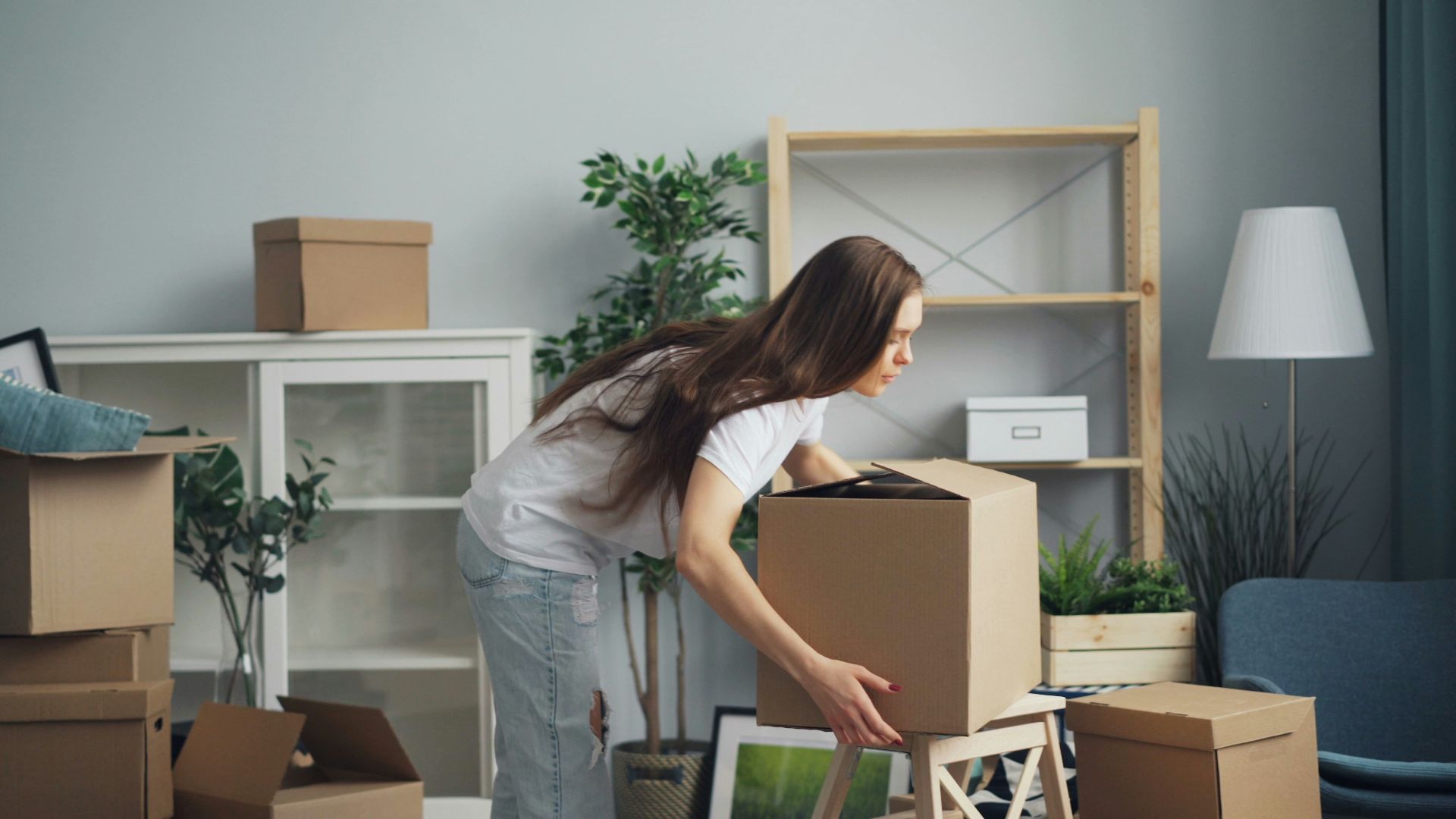 a woman moving boxes in a living room