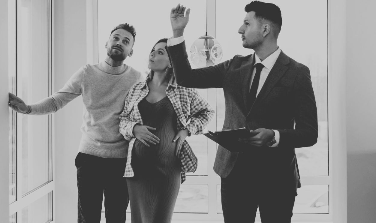 A couple tours a modern home with a real estate agent, exploring their potential new living space
