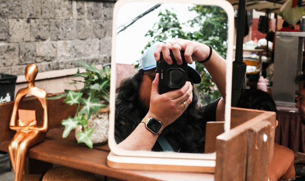 Photographer capturing his reflection in a street market mirror in Manila.