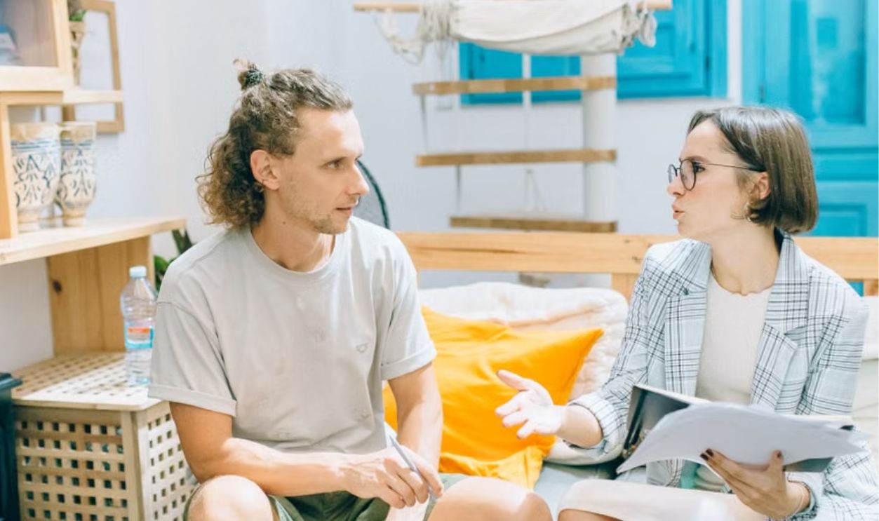 A man and woman discussing work in a stylish, bright living room setting