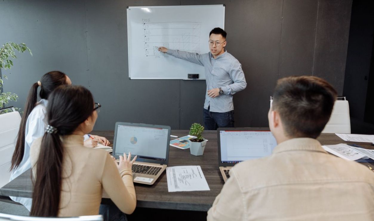 Team collaborating in a modern office with laptops and whiteboard discussions.