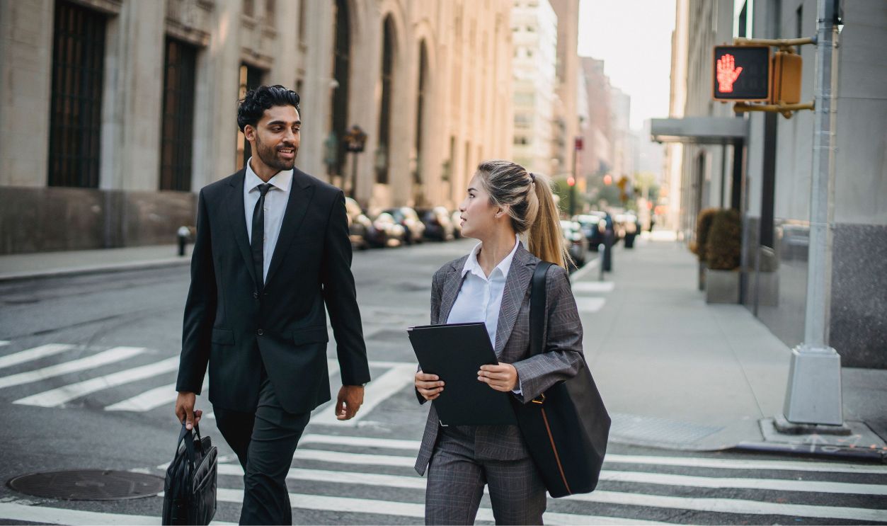 Two professionals in business attire discussing on a city street, exuding confidence