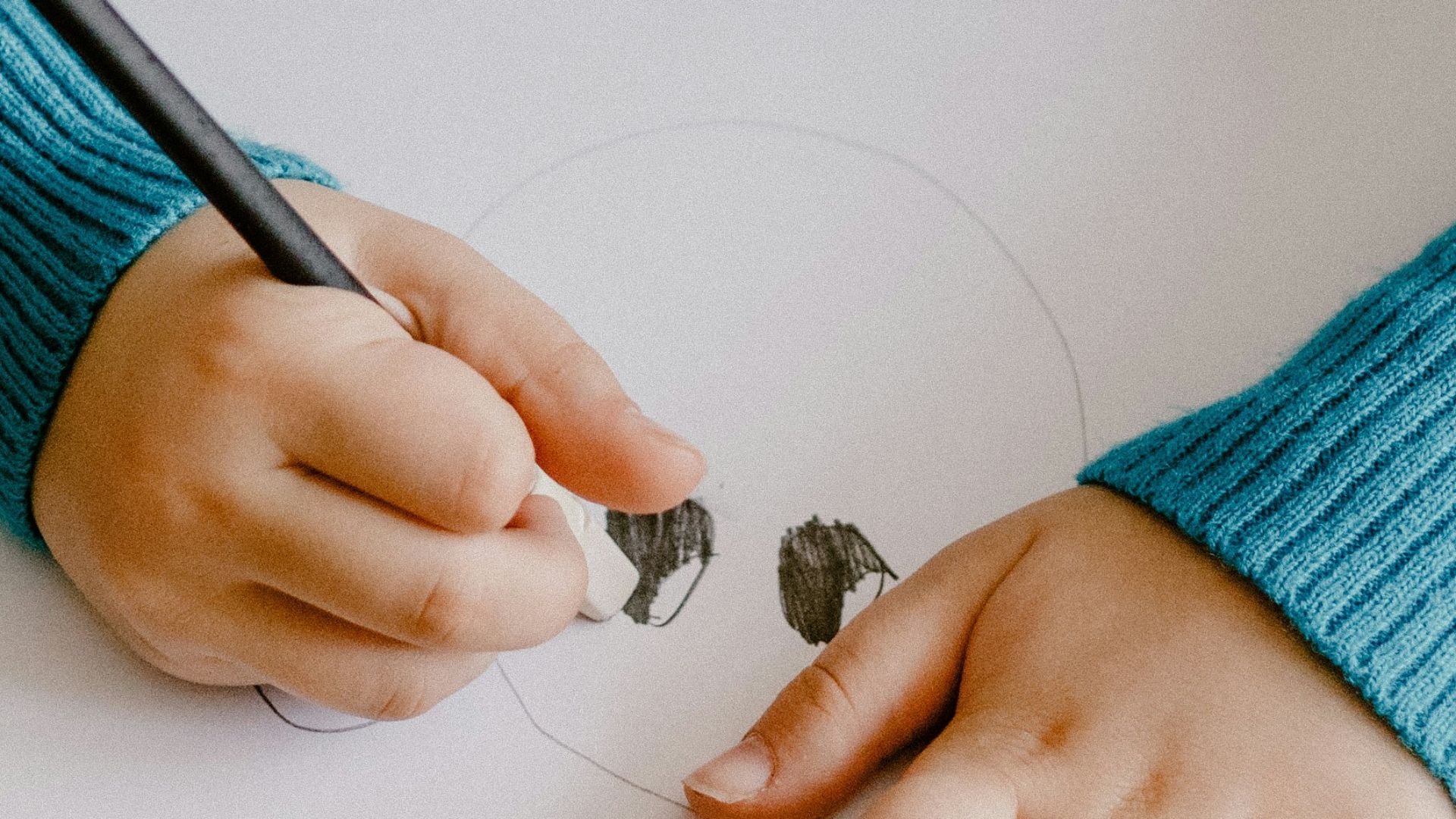 a young girl sitting at a table with colored pencils