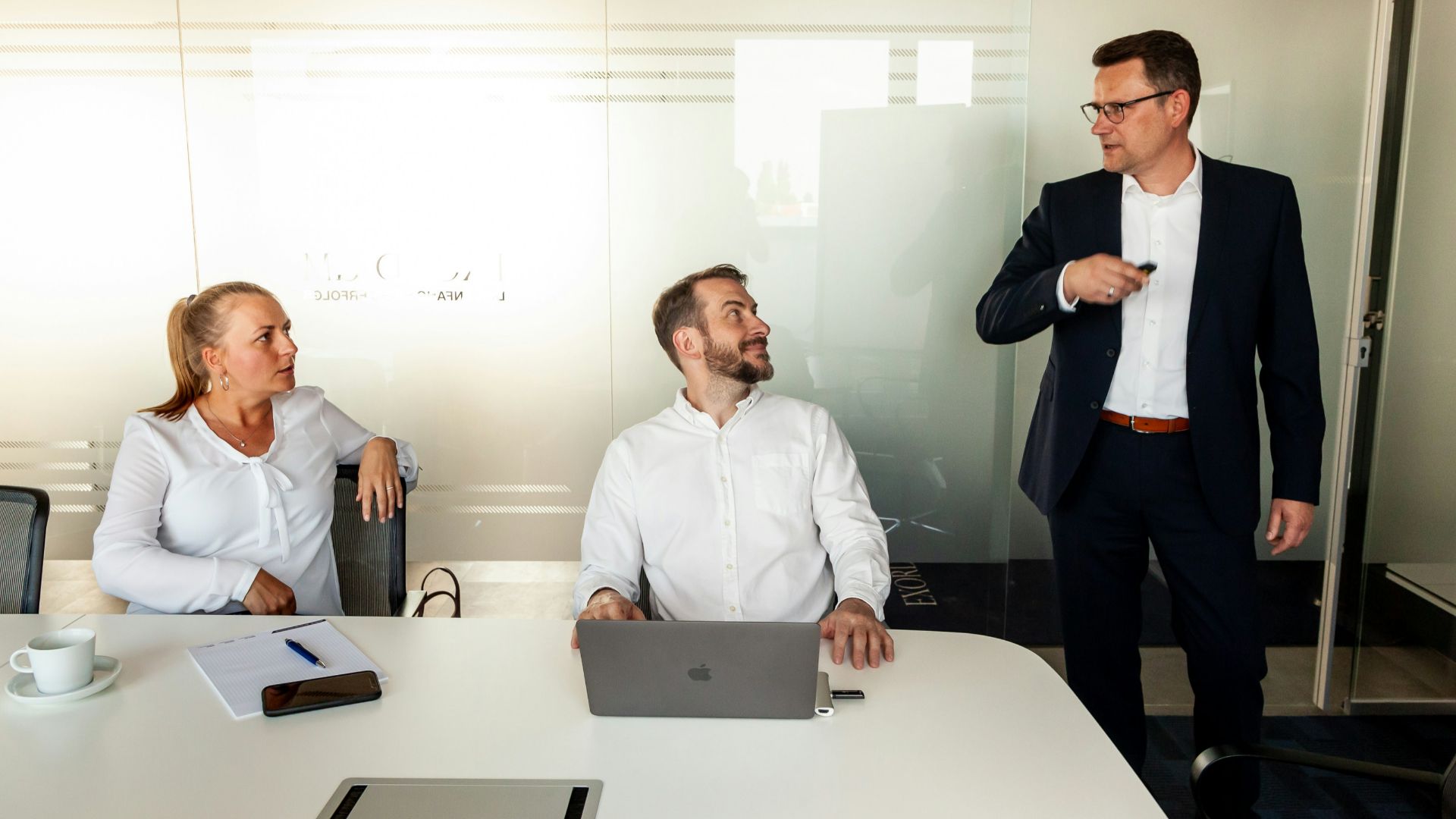 Three business people in a modern office meeting.