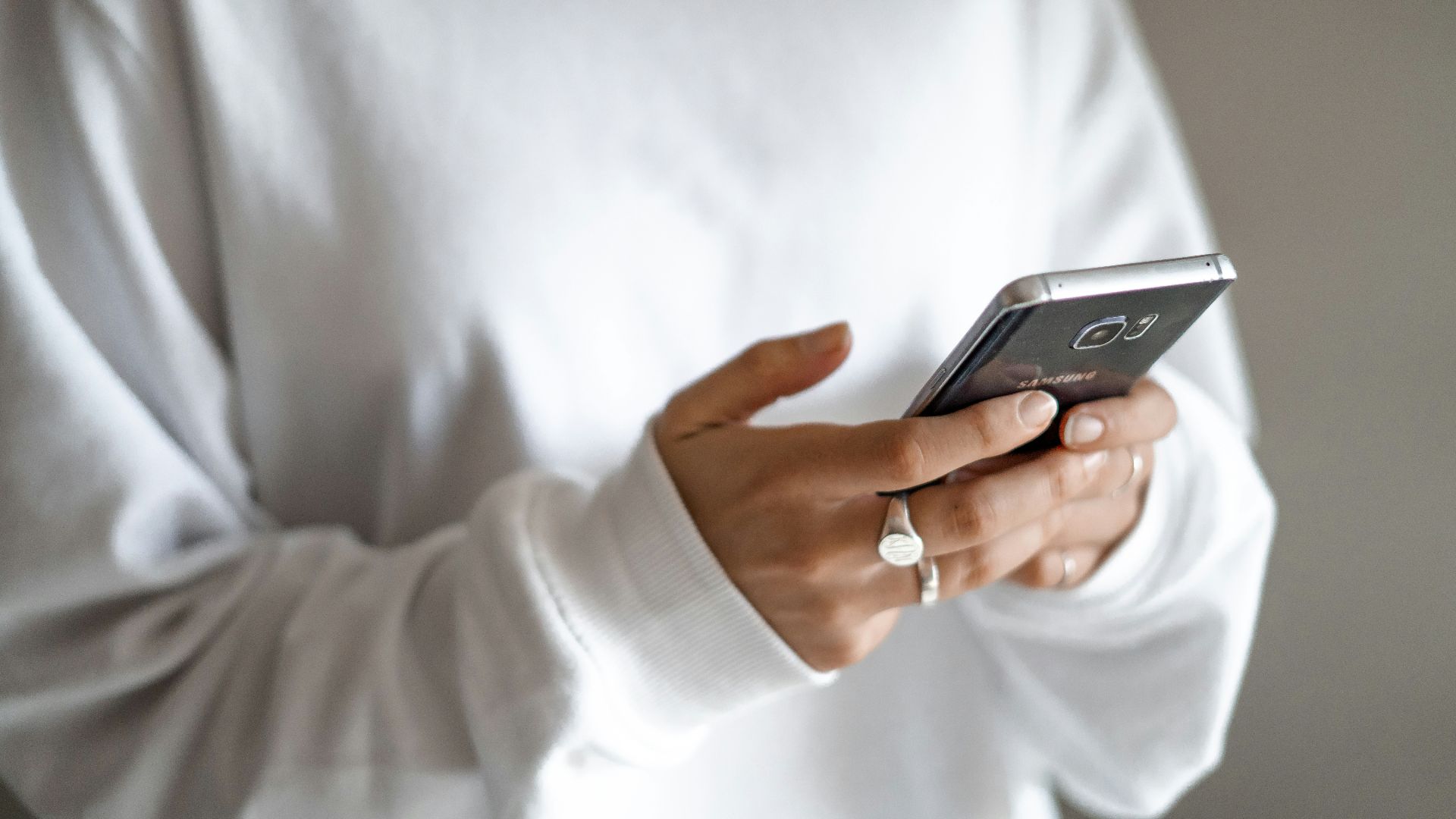 person in white long sleeve shirt holding black smartphone