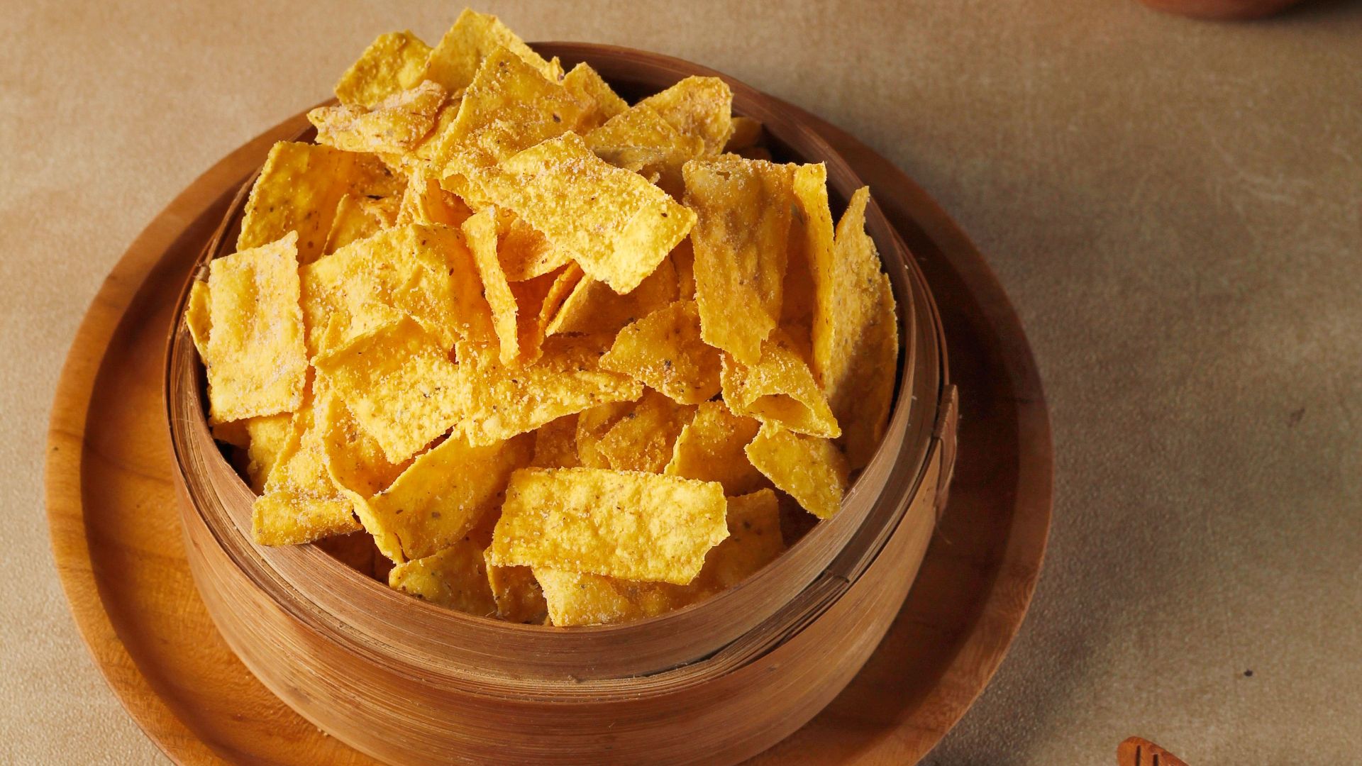 Crispy corn chips in a wooden bowl with cheese, corn, and herbs.