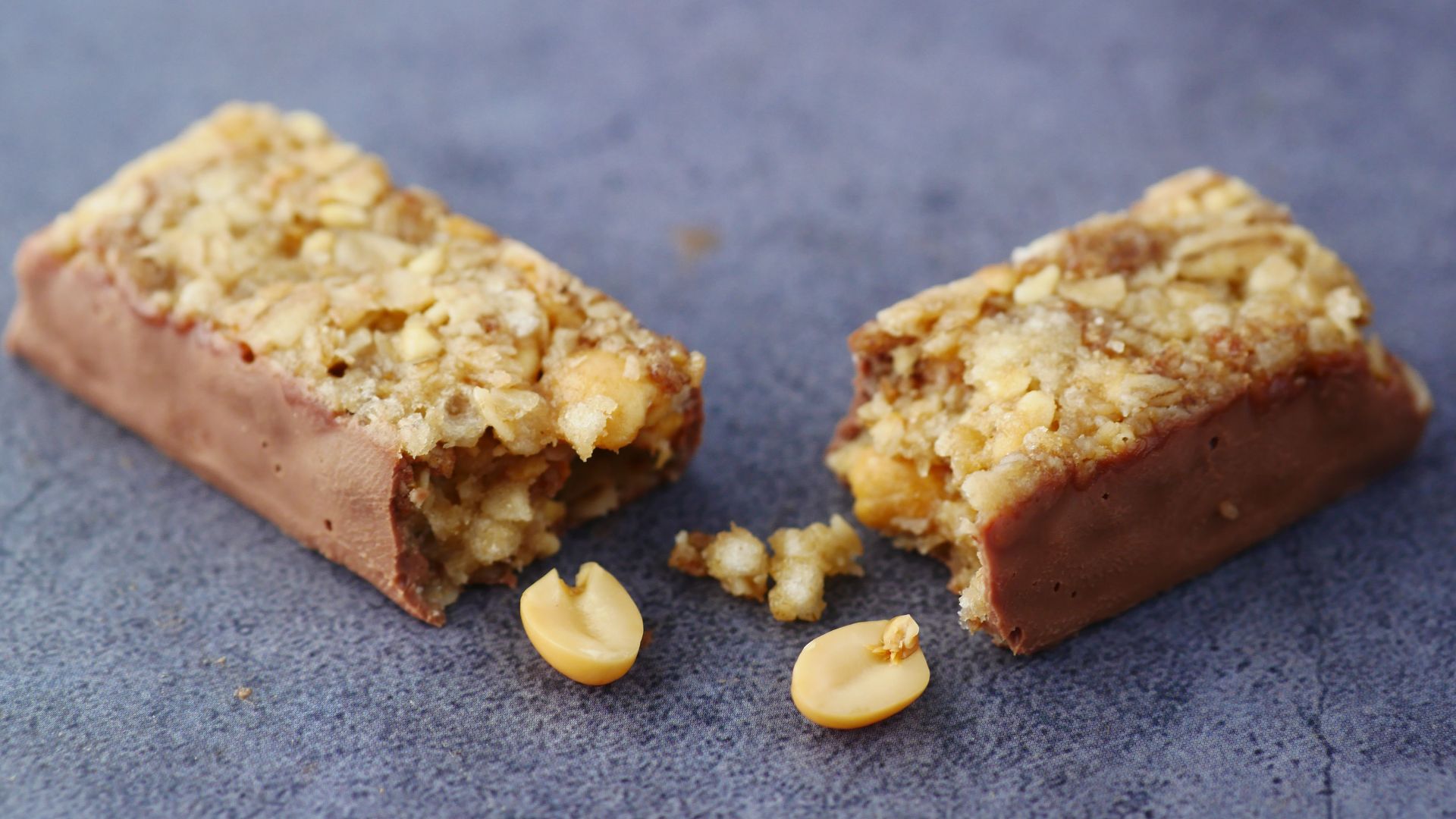 Close-up of a broken chocolate and nut energy bar on a gray surface.