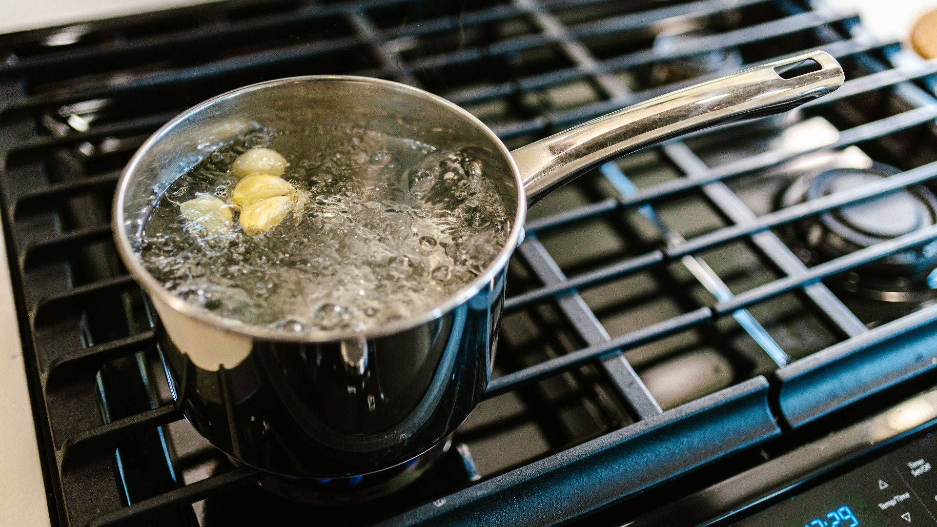 Close-up of garlic boiling in a pot on a stove, showcasing culinary preparation.