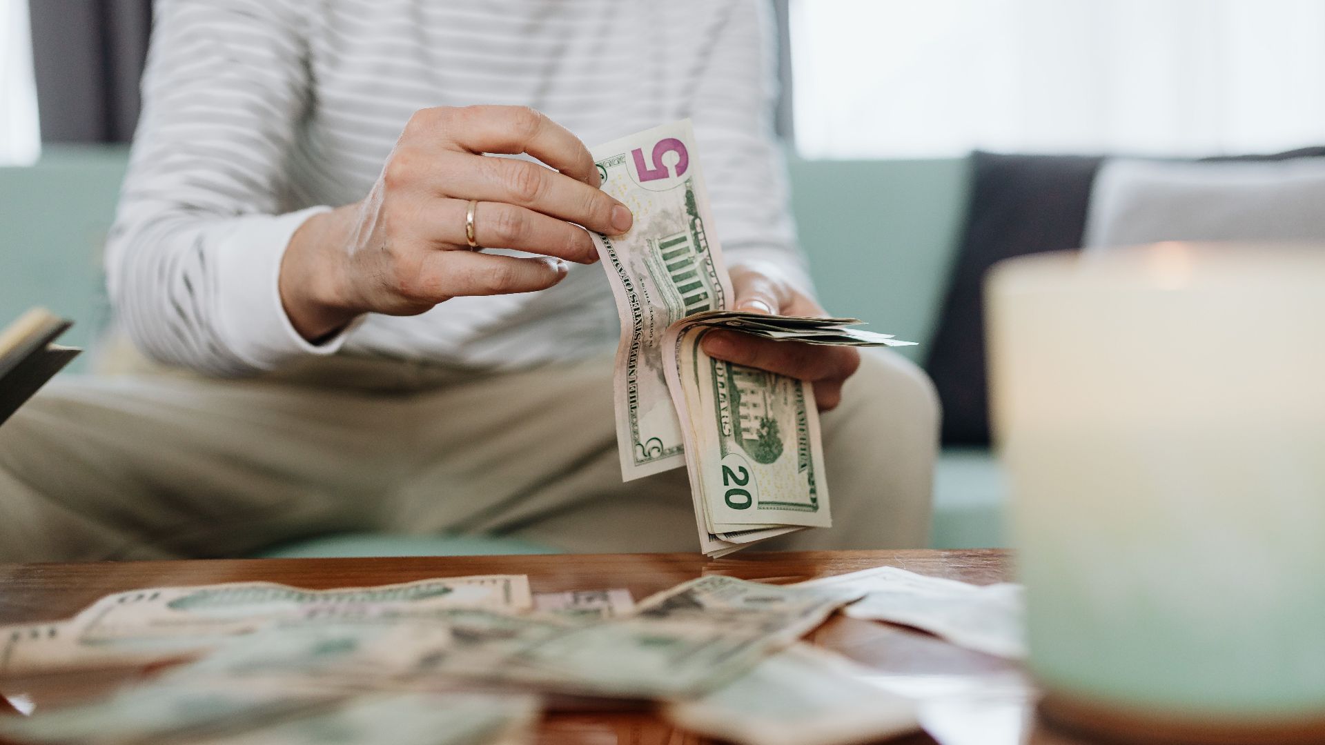 Close-up of hands counting dollar bills indoors, offering a personal finance theme.