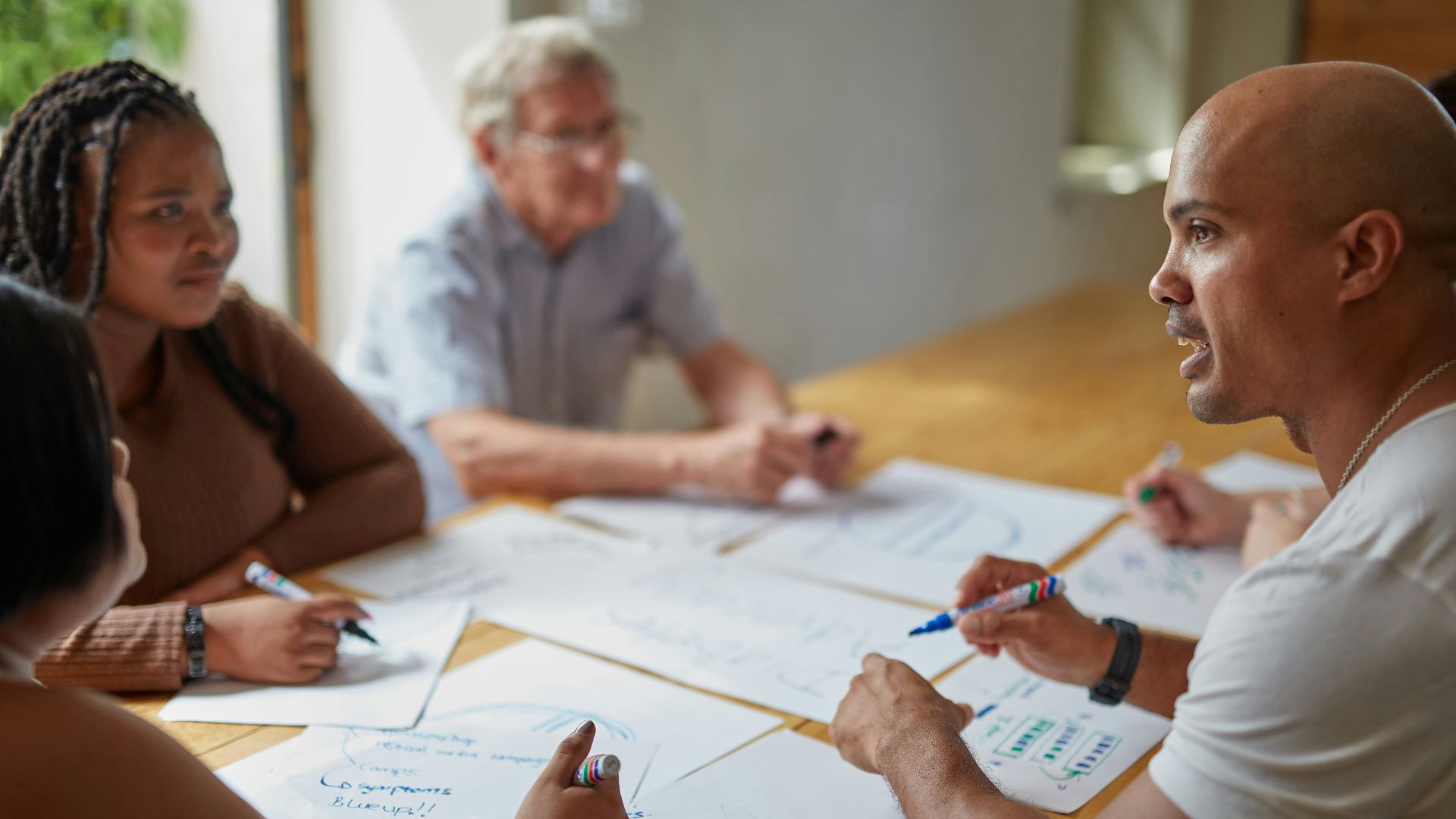 People are collaborating on papers at a table.