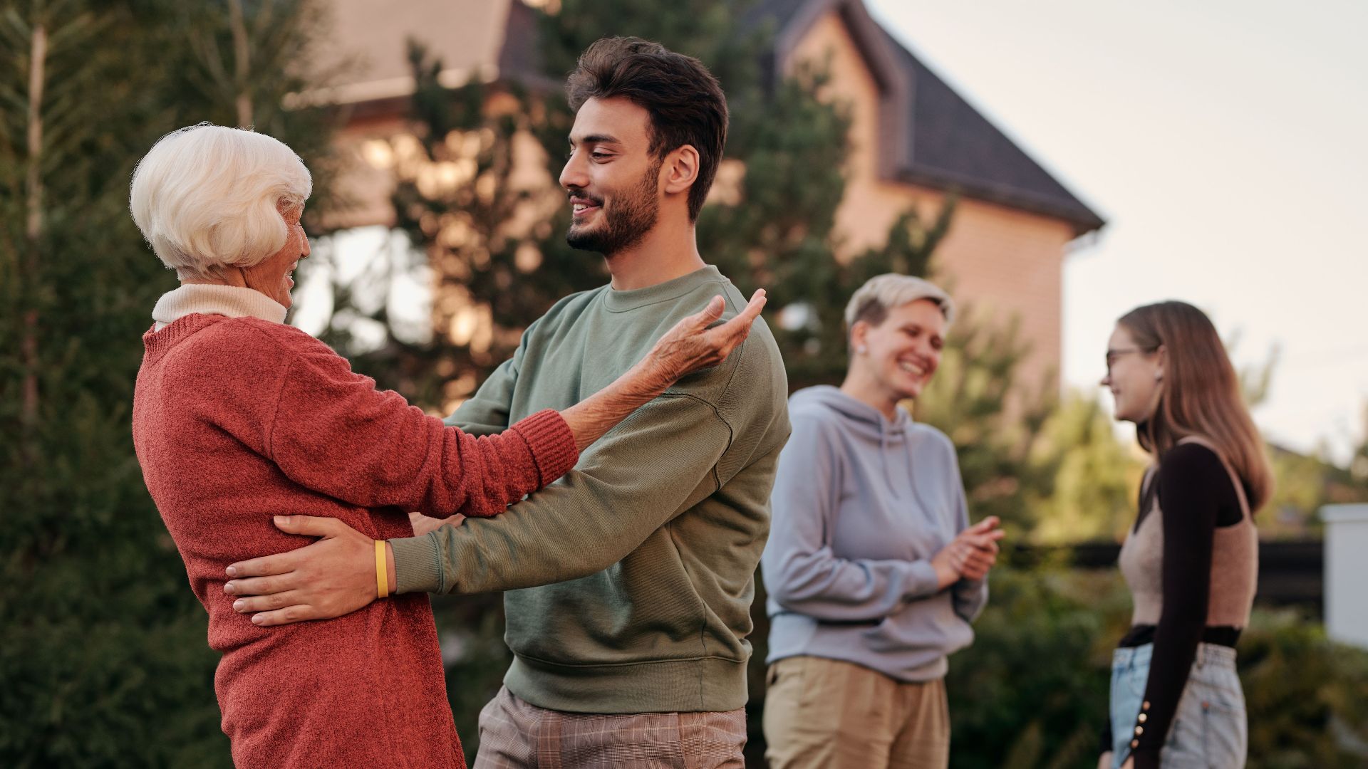 A joyful family gathering outdoors with diverse generations embracing and smiling.