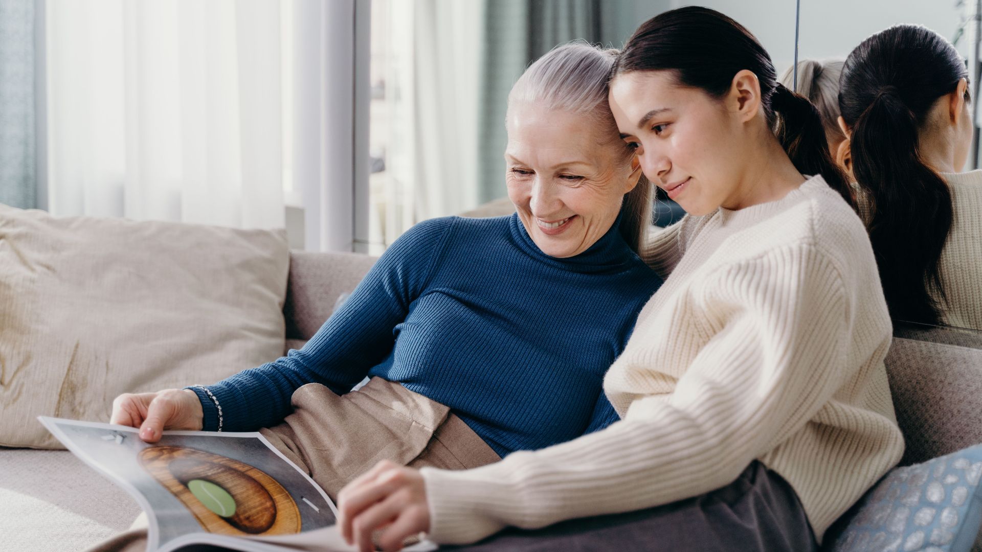 A mother and daughter sharing a joyful moment together on a comfortable couch indoors.