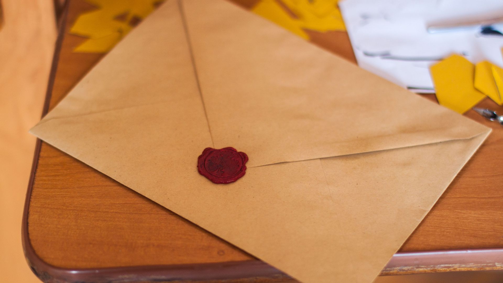 A close-up of a vintage envelope sealed with wax, lying on a wooden table.