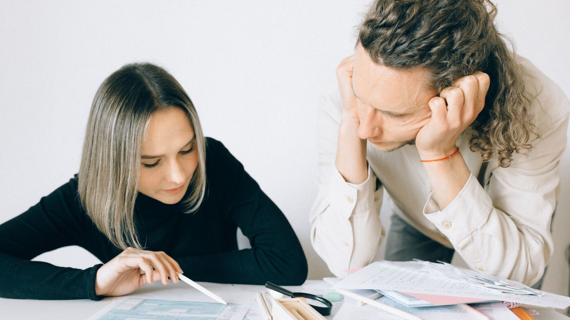 Two colleagues discussing paperwork in a modern office setting.