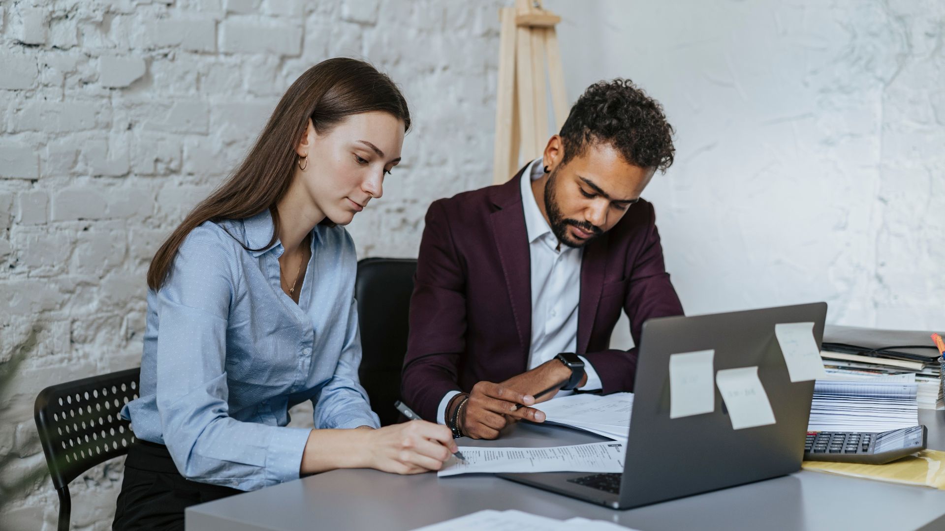Two professionals working together at a desk in a modern office environment.