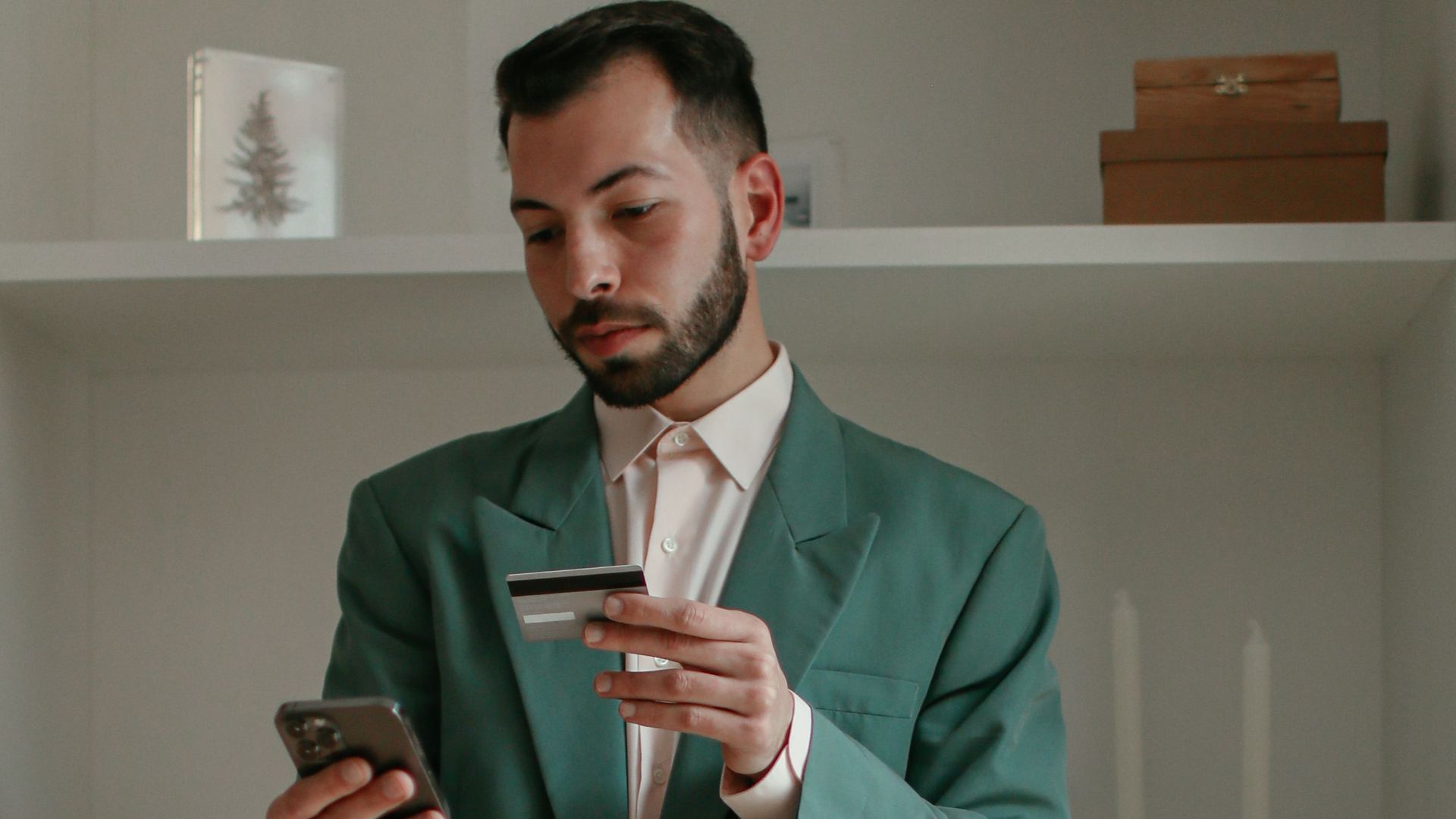 Barefoot man using smartphone and credit card for online shopping indoors. Modern lifestyle concept.