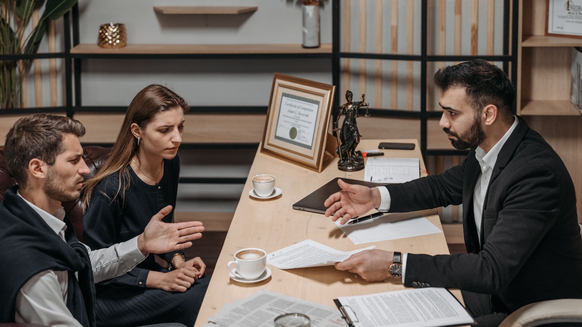 Lawyer consulting clients in an office. Documents and coffee on the table.