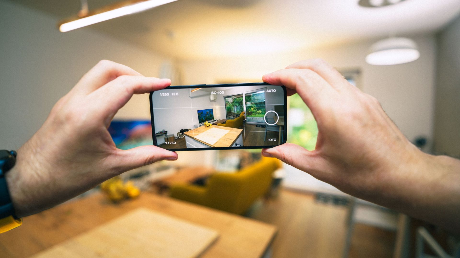 Hands capturing a modern living room interior with a smartphone.