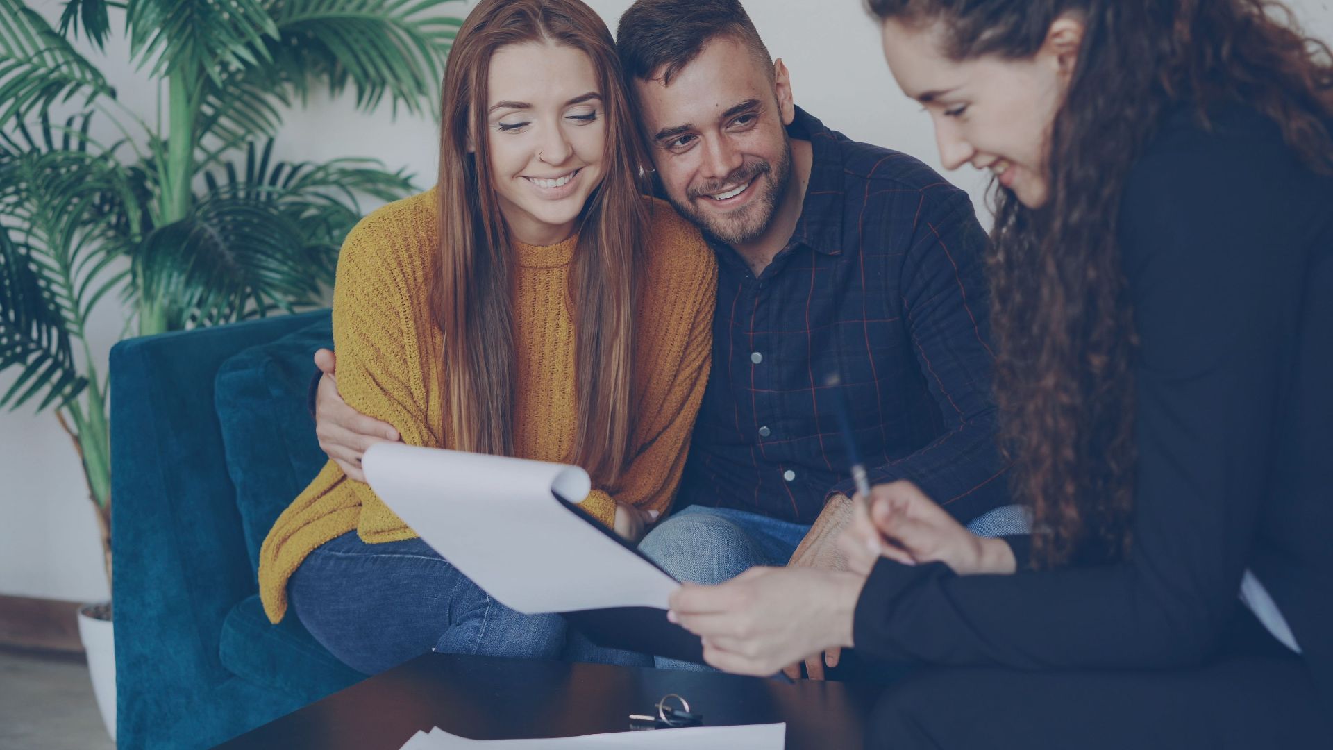 Happy couple discussing finance with advisor in cozy office setting.