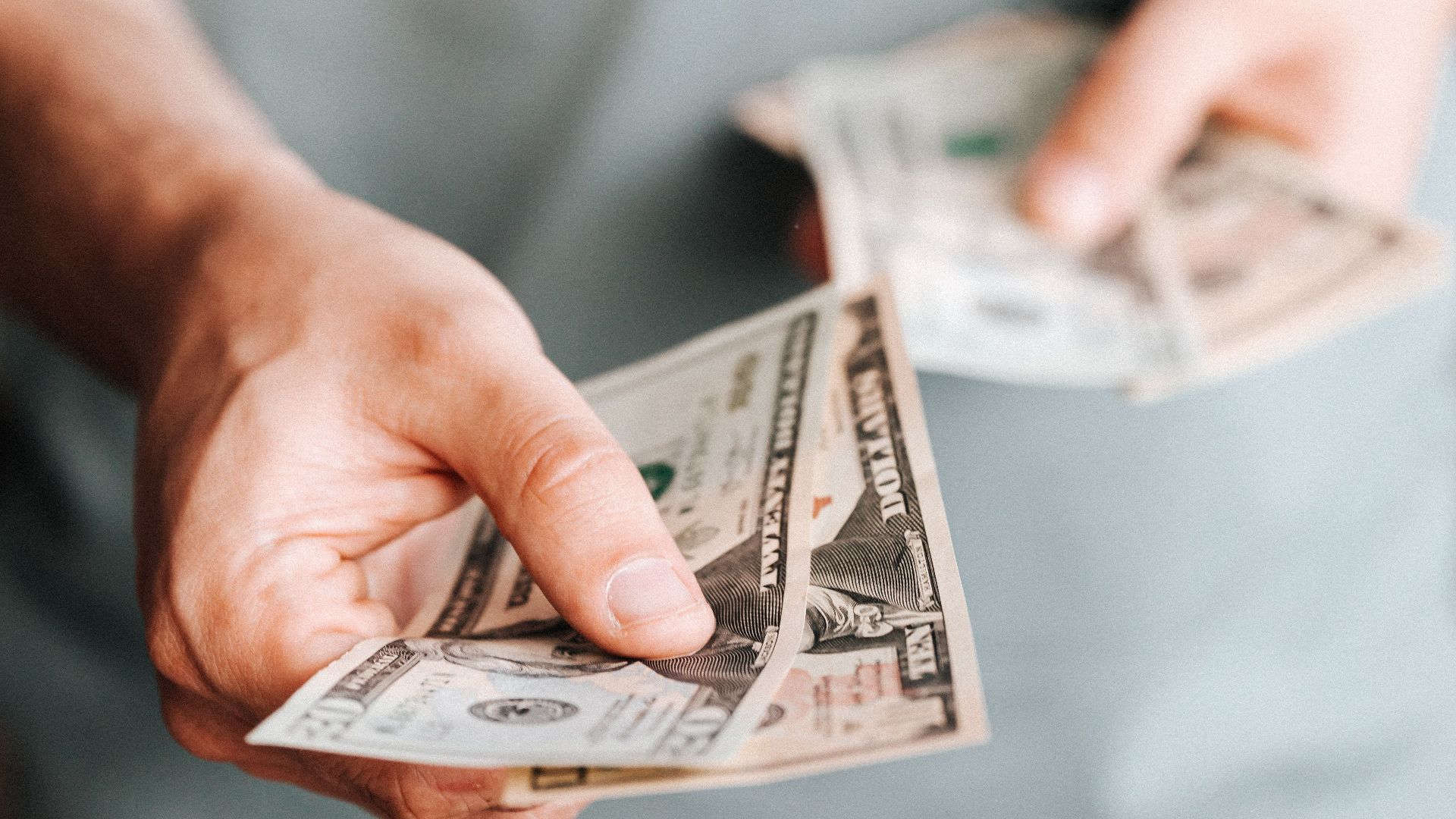 Unrecognizable male in casual clothes holding cash and paying with paper banknotes