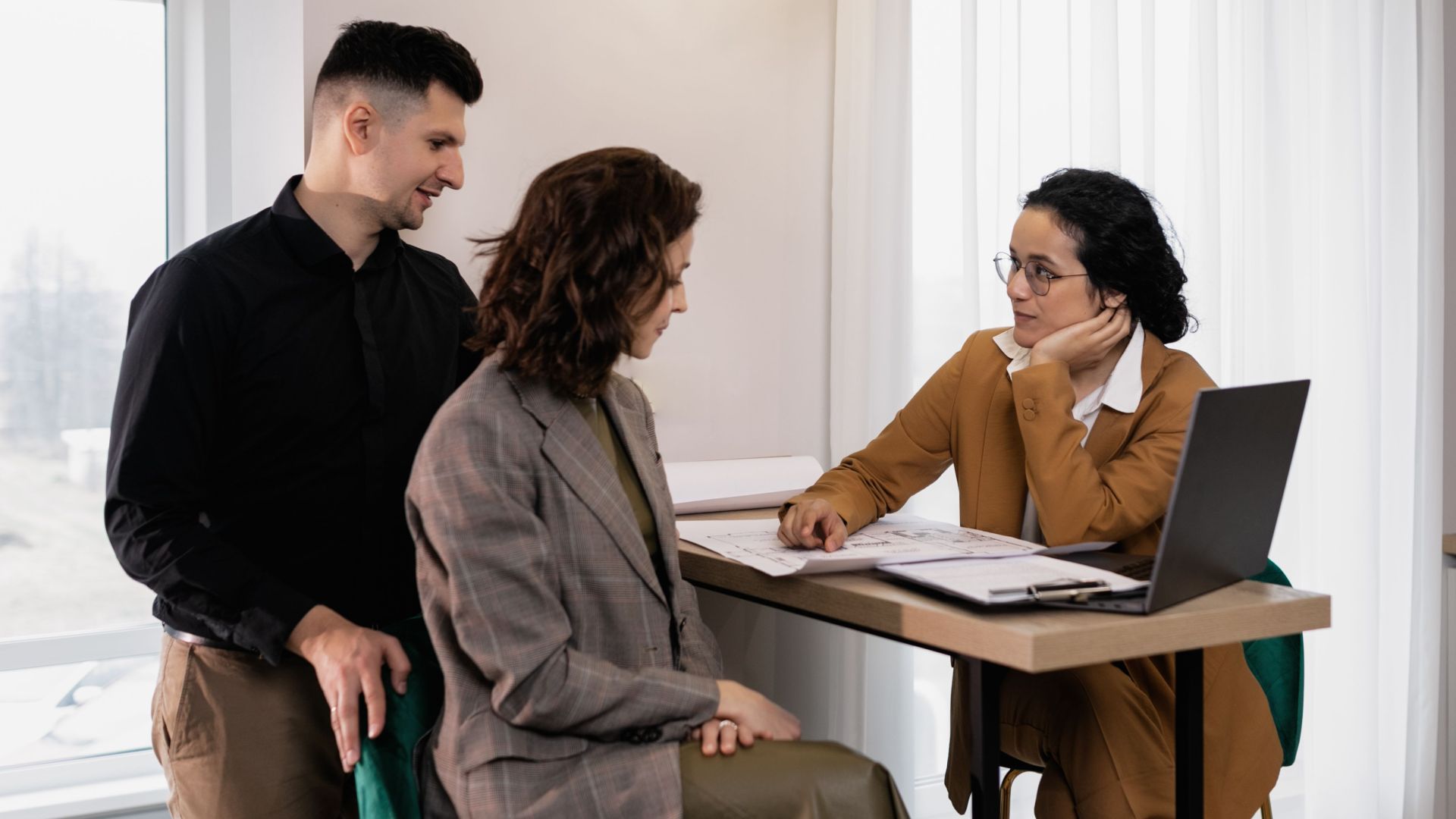 A couple consults a real estate agent in a modern office setting.
