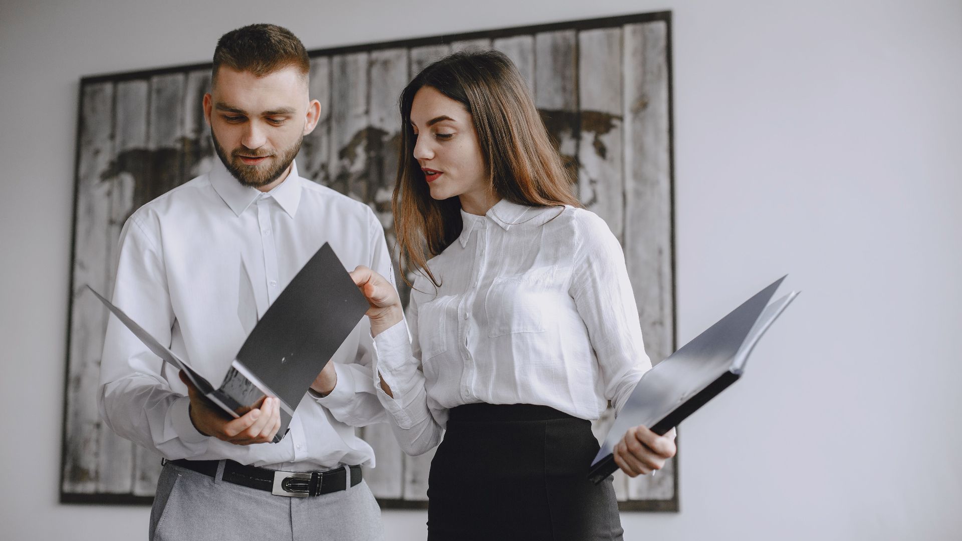 Two colleagues in a modern office reviewing documents together.