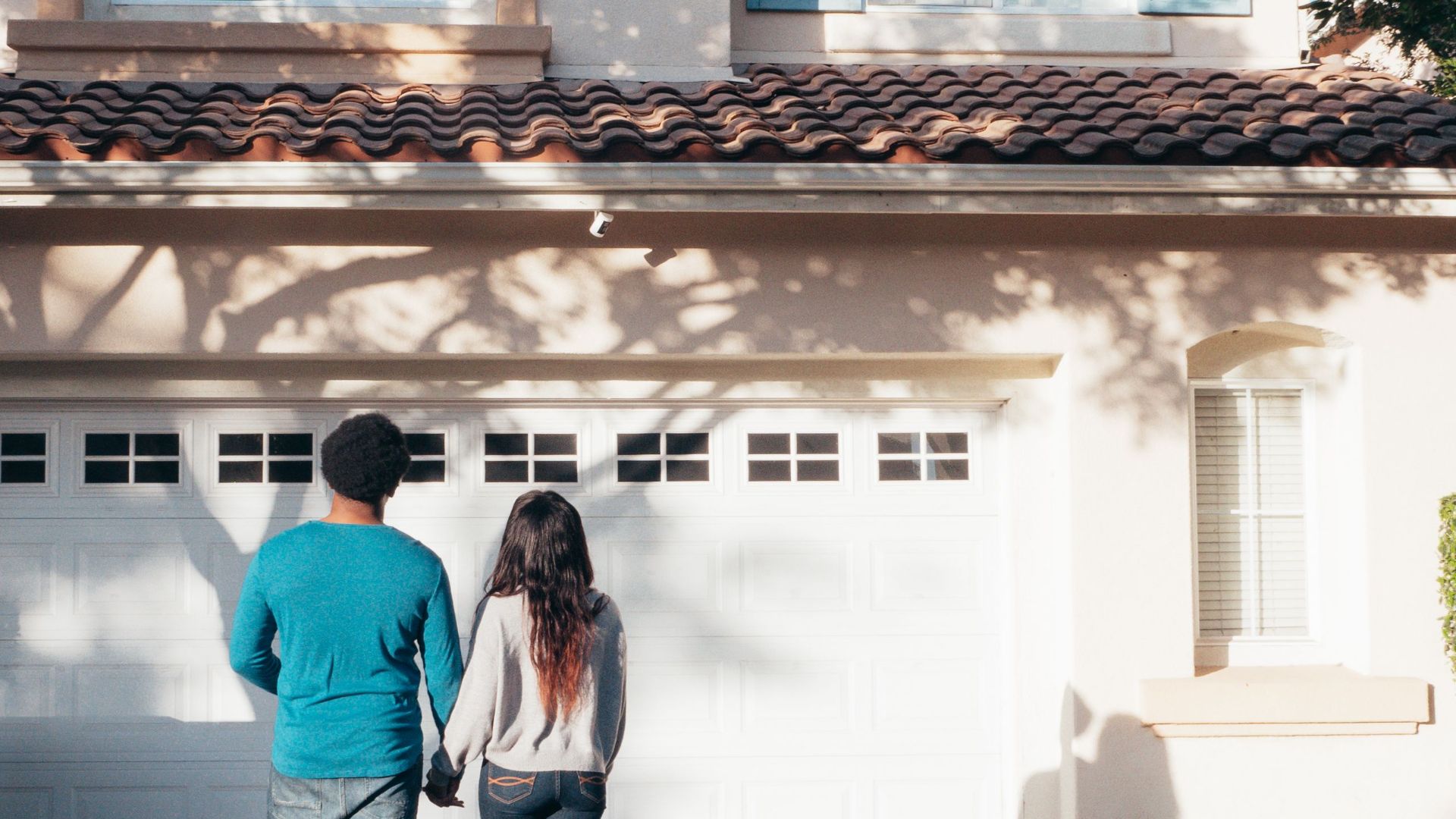 A couple stands hand in hand, admiring their new house and life ahead.