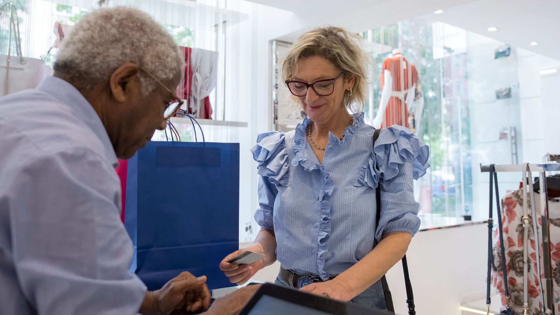 Elegant seniors making a cashless payment in a stylish clothing store. A moment of modern shopping.