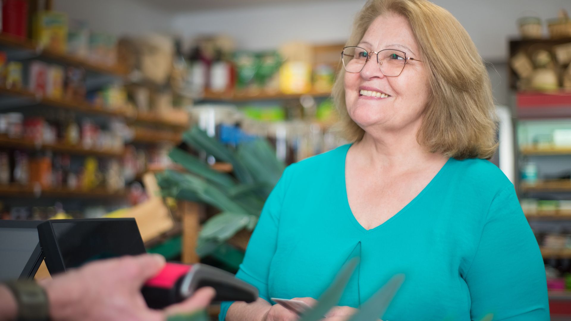 A happy senior woman making a purchase at a local store in Portugal.