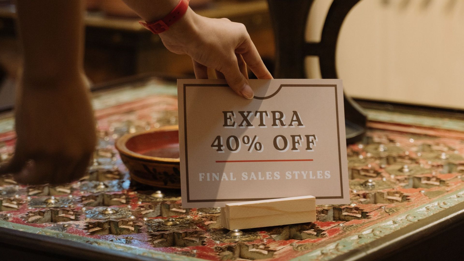 A woman places a sign with 40% discount in a boutique setting, highlighting a sale.